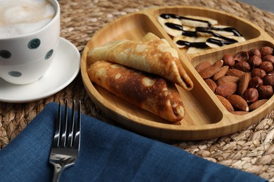 Delicious crepes with banana, nuts, chocolate sauce and coffee on table, closeup