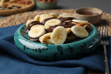 Photo of Delicious crepes with banana and chocolate paste on table, closeup