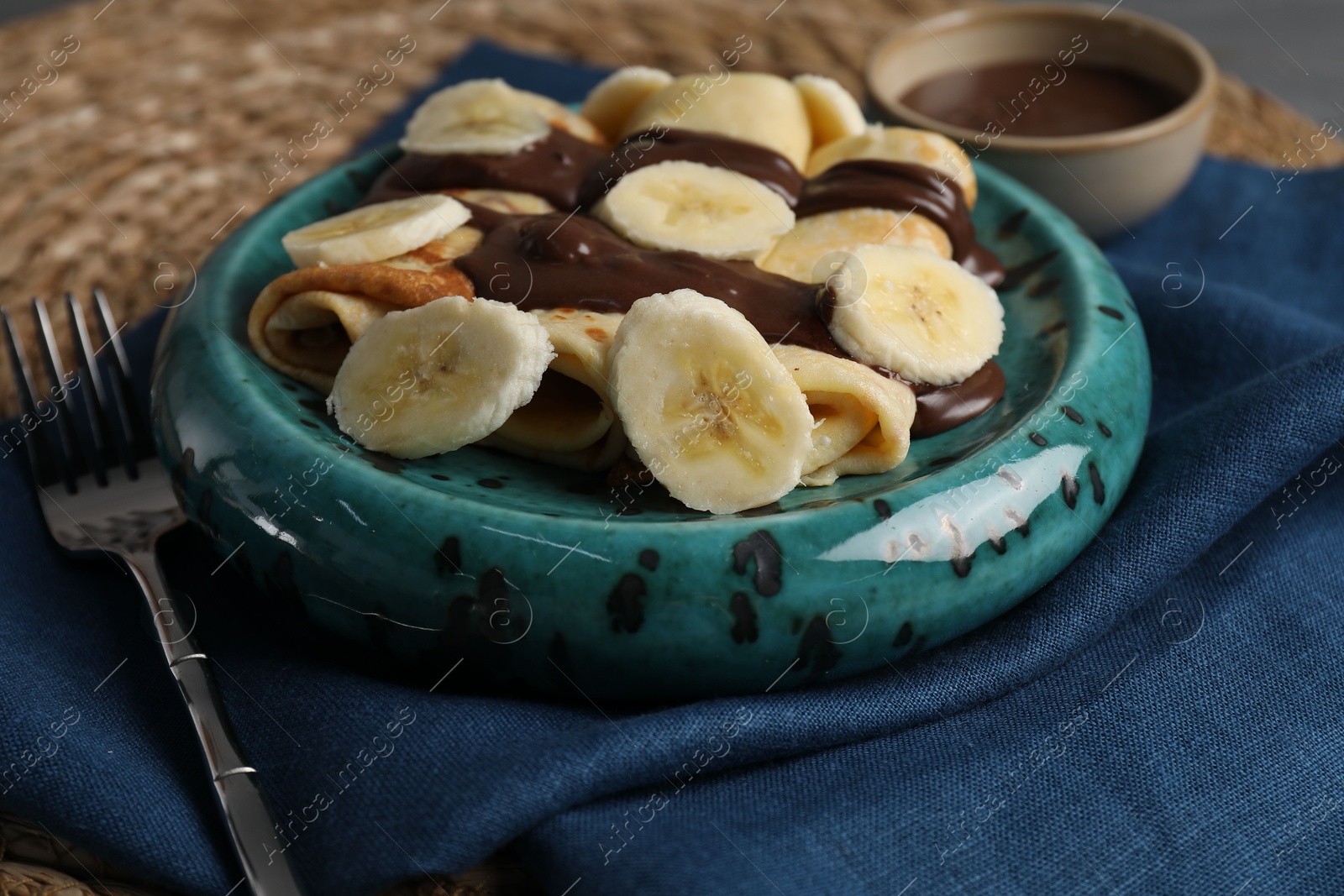 Photo of Delicious crepes with banana and chocolate paste on table, closeup