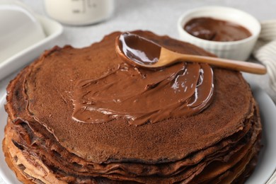 Photo of Delicious chocolate crepes with sweet paste on table, closeup