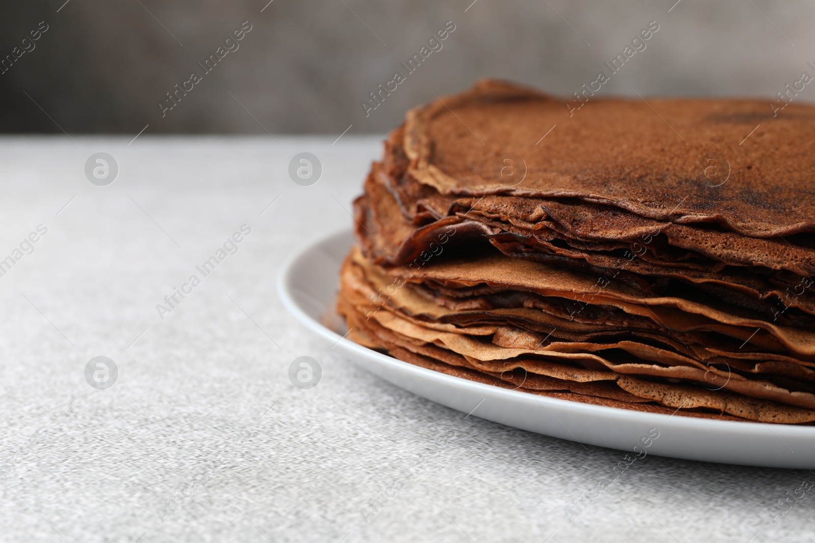 Photo of Delicious chocolate crepes on light grey table, closeup. Space for text