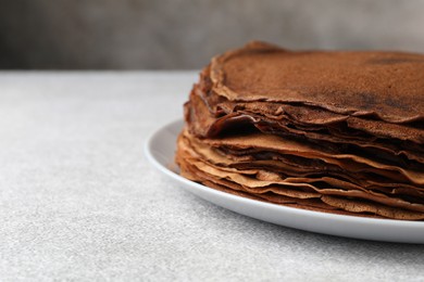 Photo of Delicious chocolate crepes on light grey table, closeup. Space for text