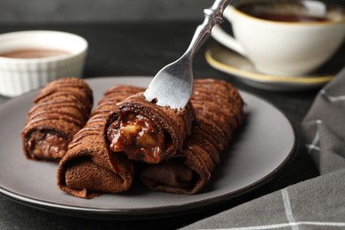 Photo of Delicious chocolate crepes with sweet paste and nuts on table, closeup