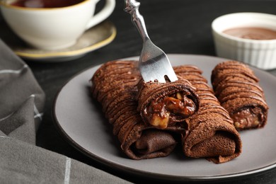 Photo of Delicious chocolate crepes with sweet paste and nuts on table, closeup