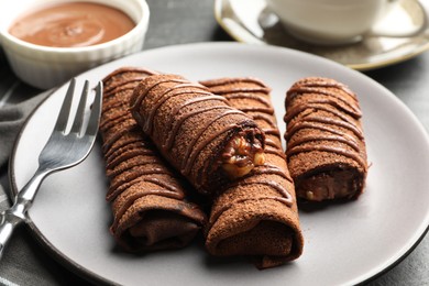 Photo of Delicious chocolate crepes with sweet paste and nuts on table, closeup