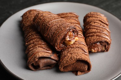 Photo of Delicious chocolate crepes with sweet paste and nuts on table, closeup