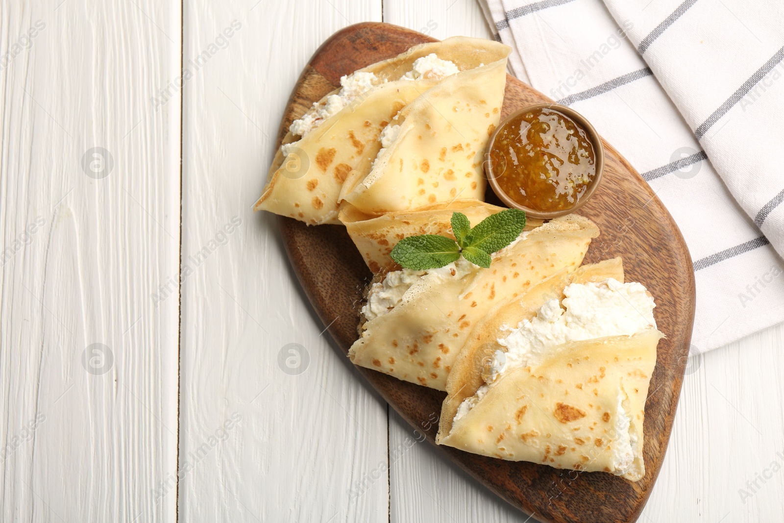 Photo of Delicious crepes with cottage cheese, jam and mint on white wooden table, top view. Space for text