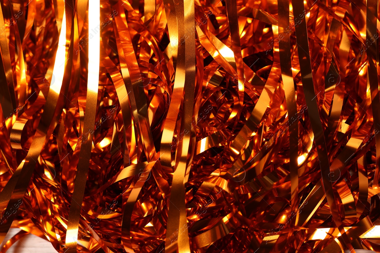 Photo of Shiny golden tinsel as background, closeup view