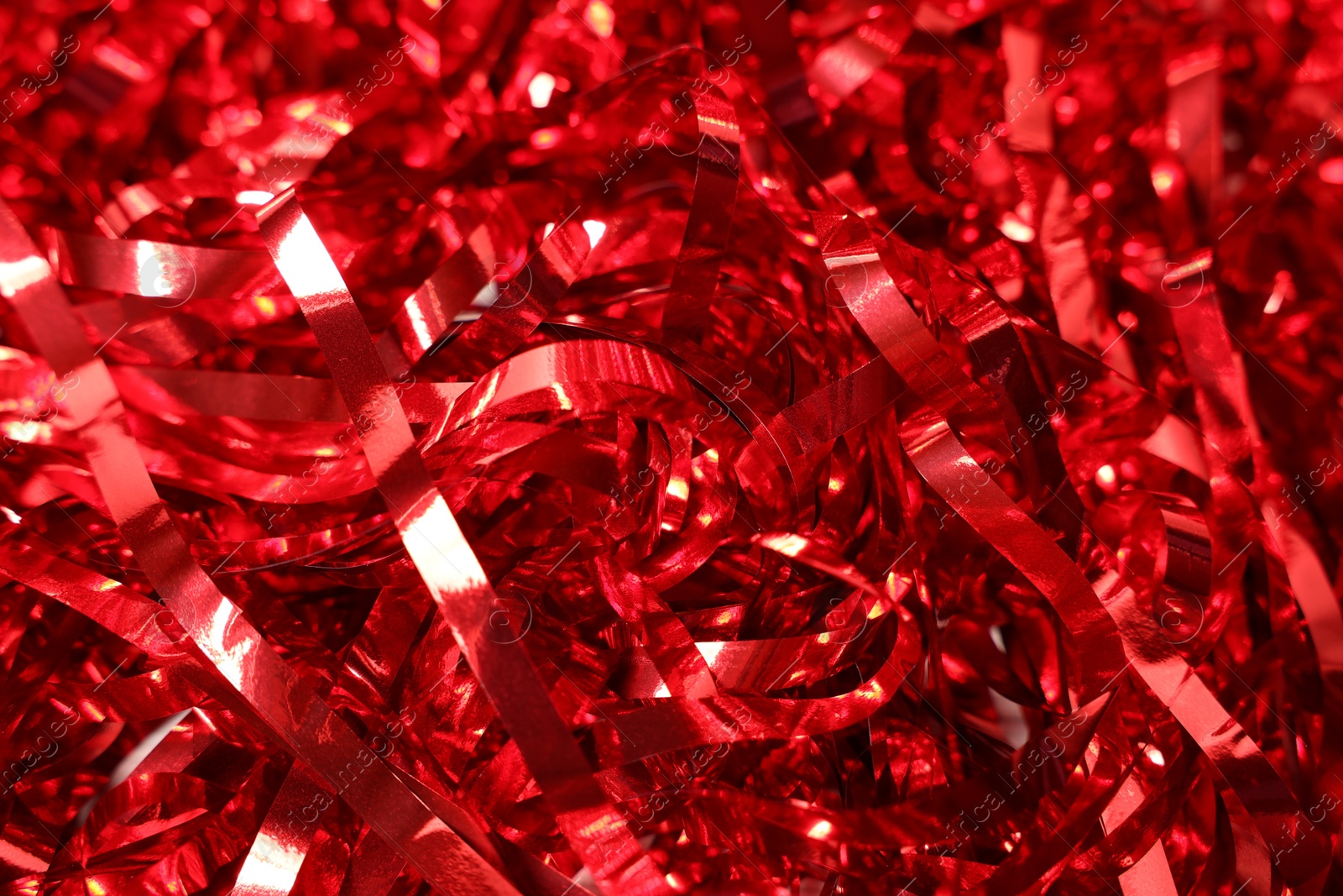 Photo of Shiny red tinsel as background, closeup view