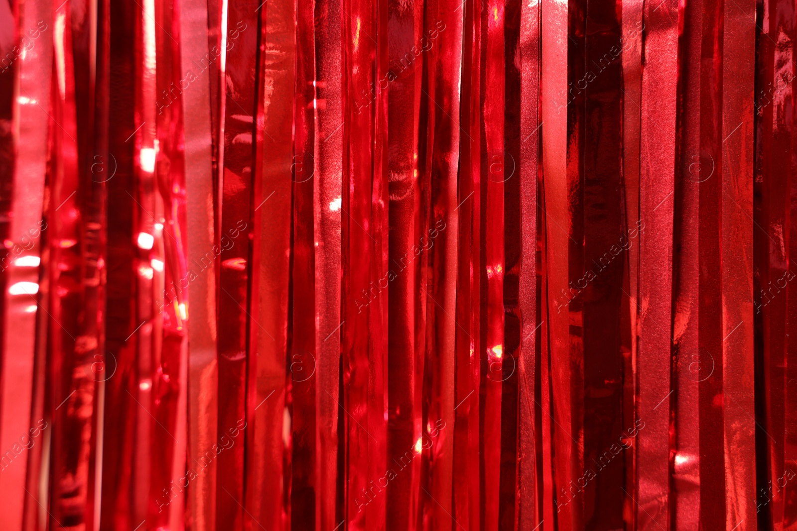 Photo of Shiny red foil curtain as background, closeup