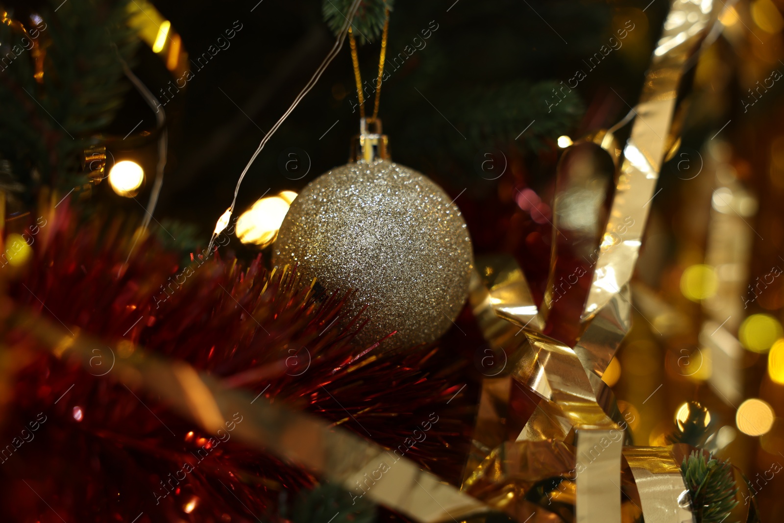 Photo of Shiny tinsels and bauble on Christmas tree, closeup