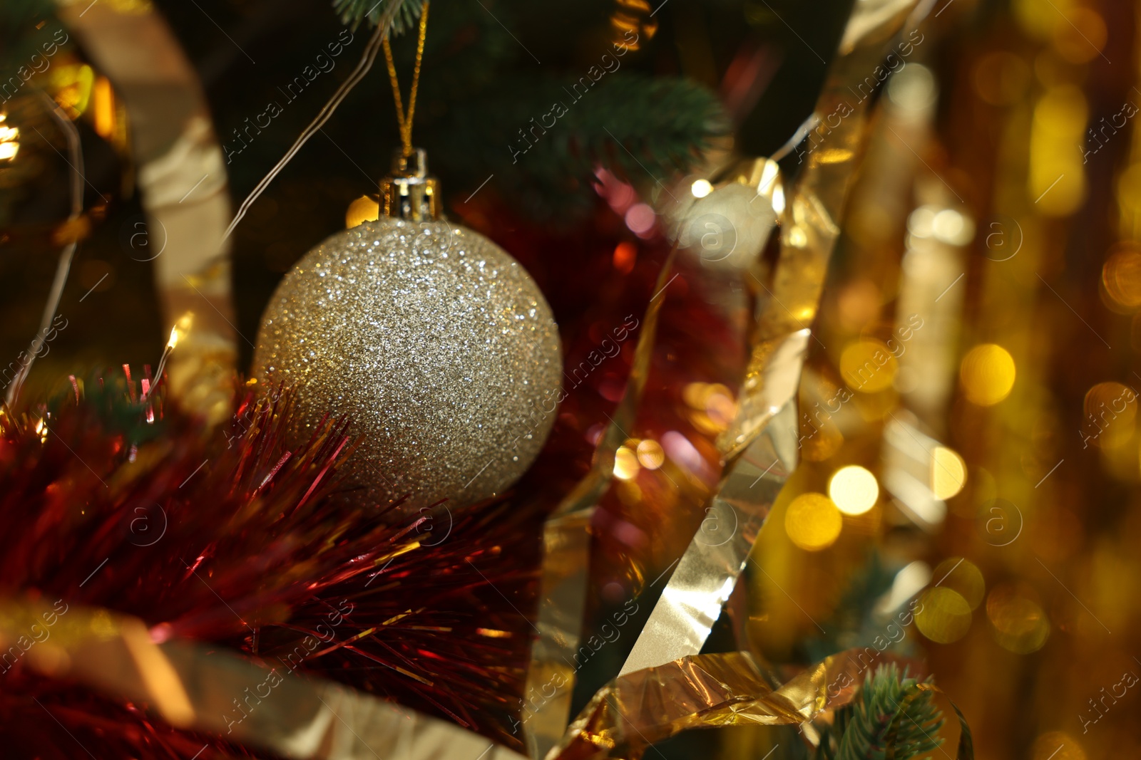 Photo of Shiny tinsels and bauble on Christmas tree, closeup