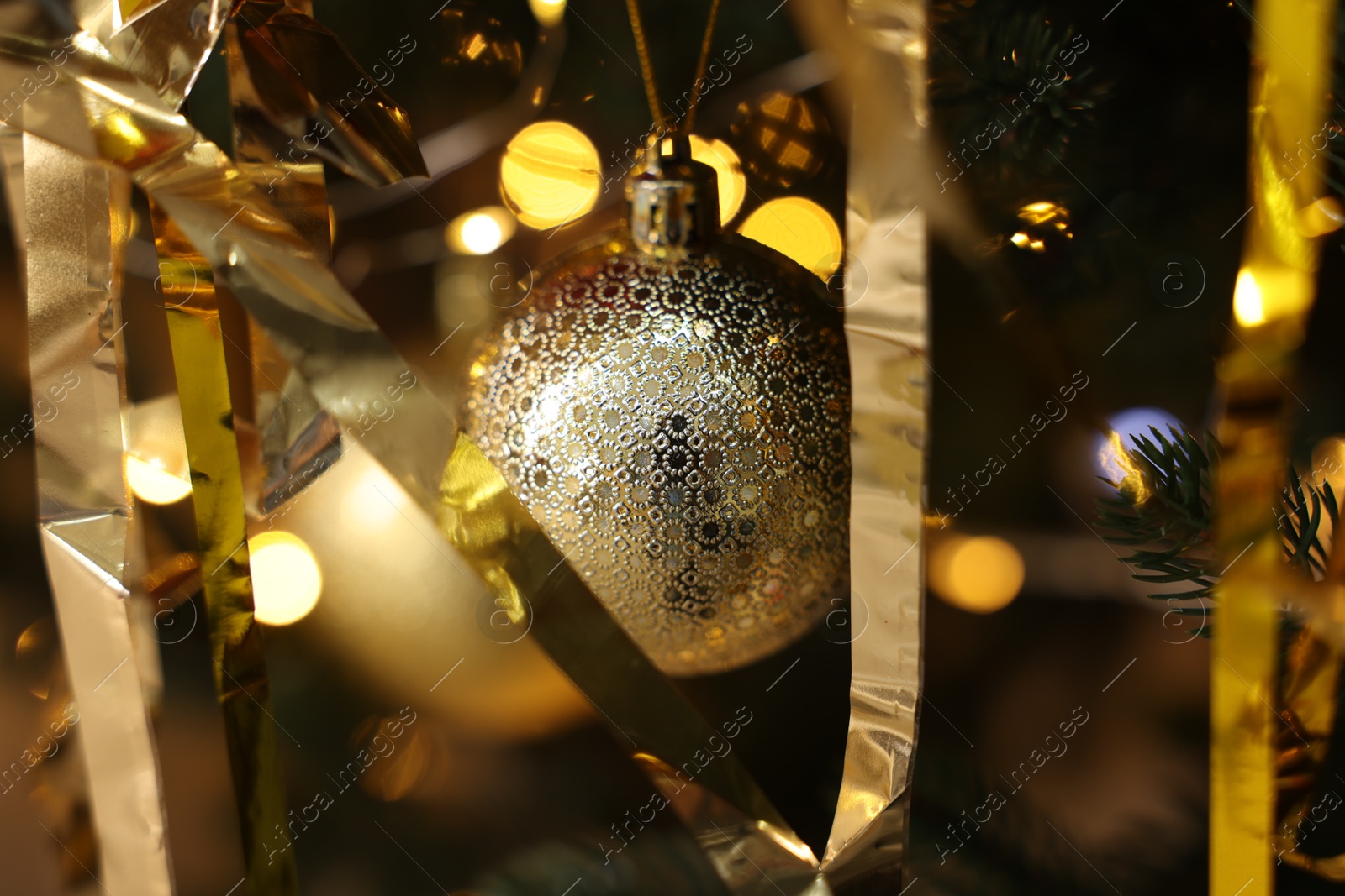 Photo of Shiny tinsels and bauble on Christmas tree, closeup