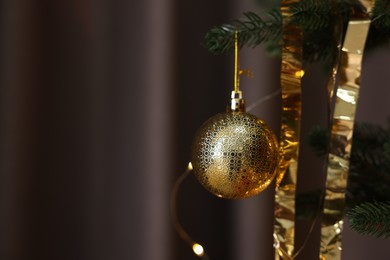 Photo of Shiny tinsels and bauble on Christmas tree against dark background, closeup. Space for text