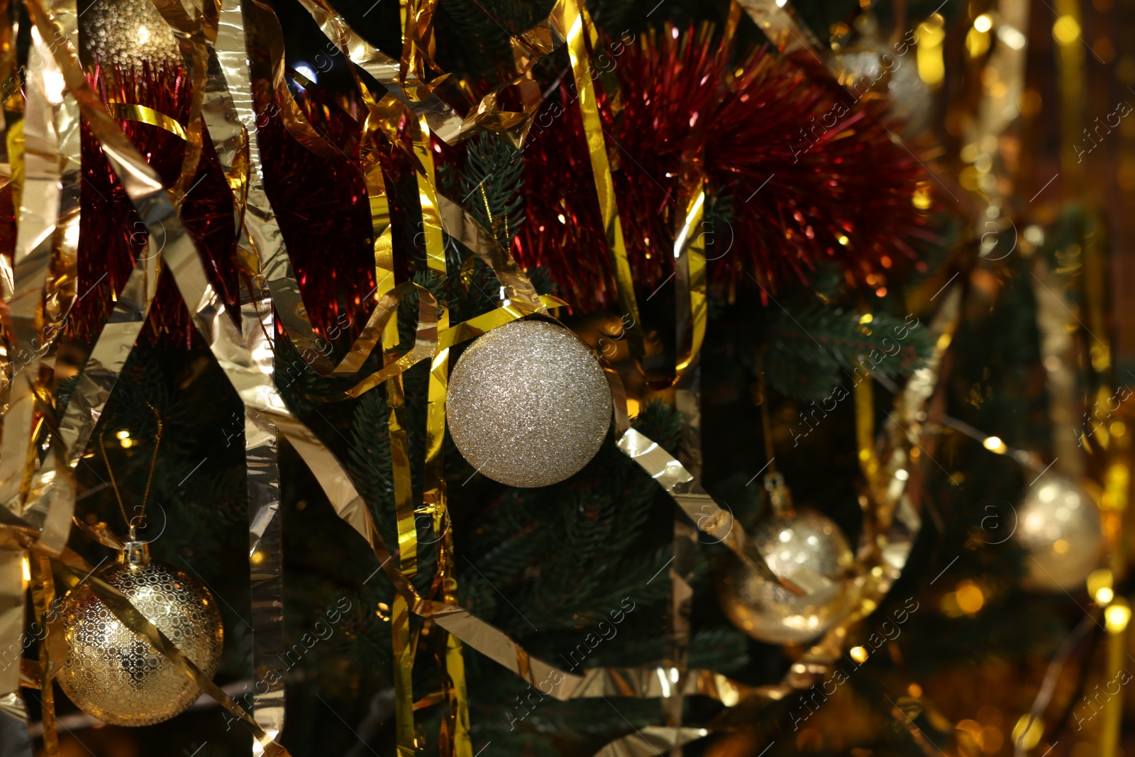 Photo of Shiny tinsels and baubles on Christmas tree, closeup