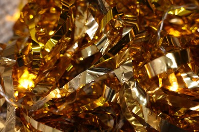 Photo of Shiny golden tinsel as background, closeup view