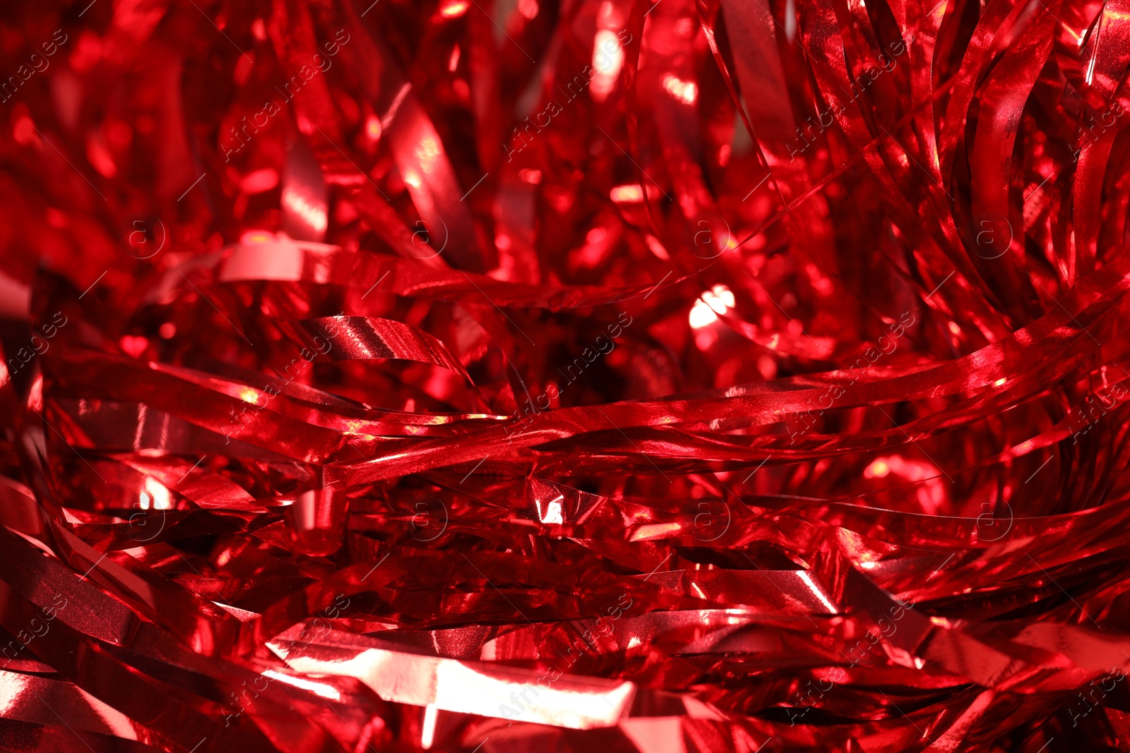 Photo of Shiny red tinsel as background, closeup view