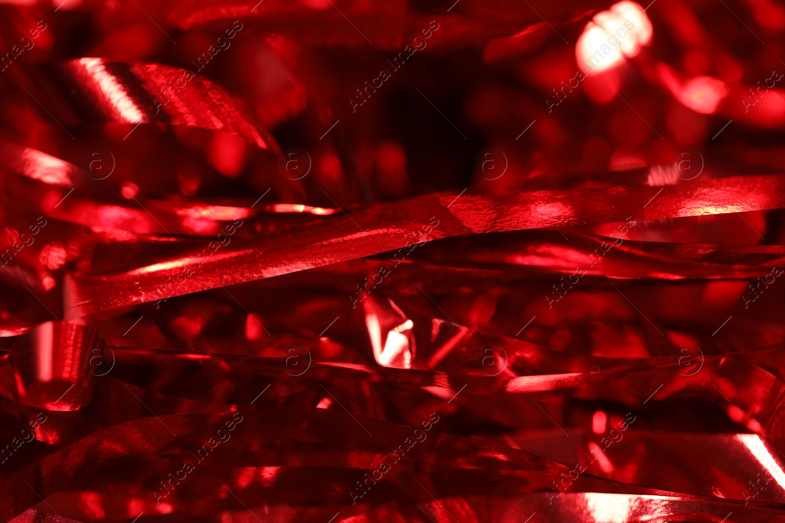 Photo of Shiny red tinsel as background, closeup view