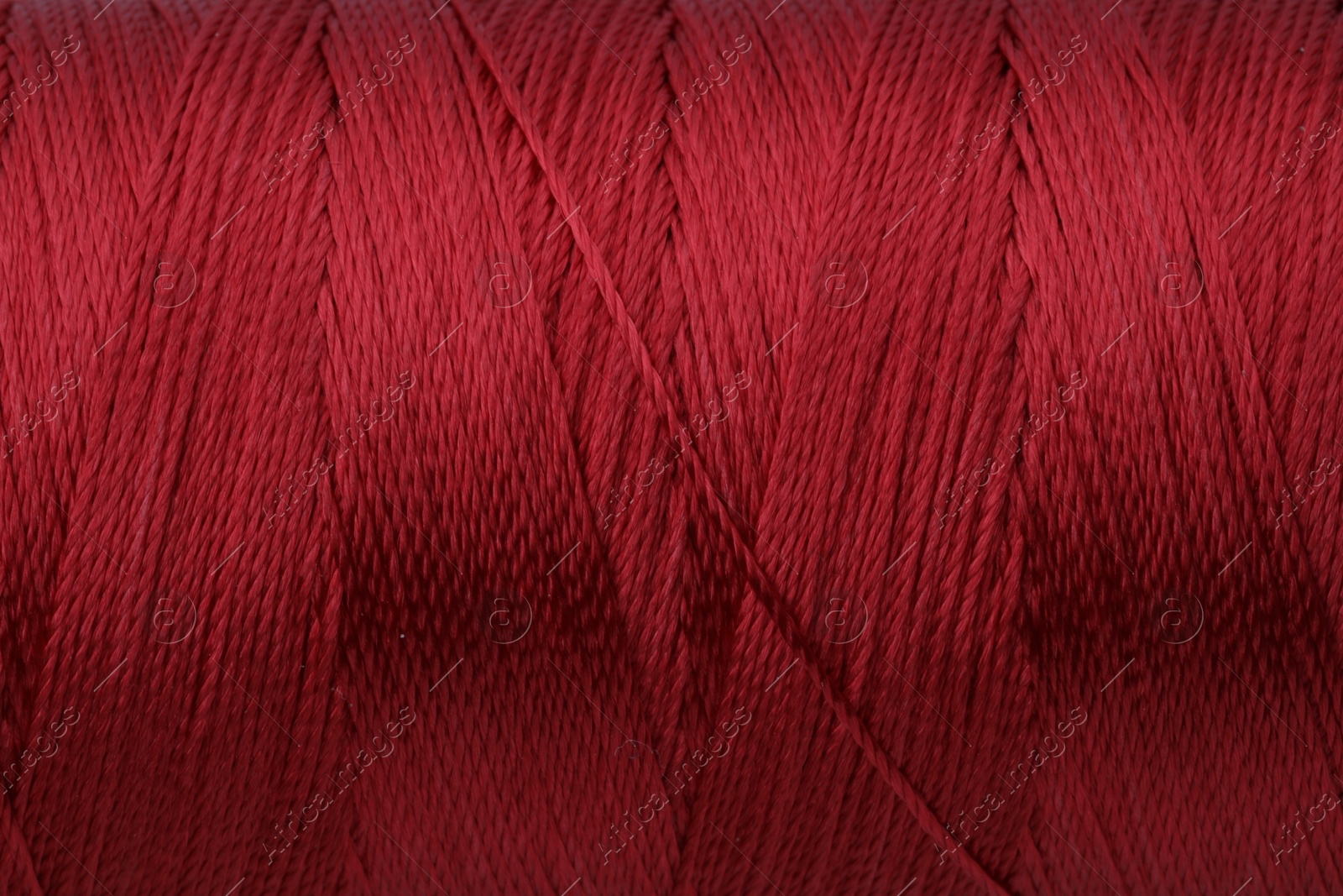 Photo of Beautiful red sewing thread as background, closeup