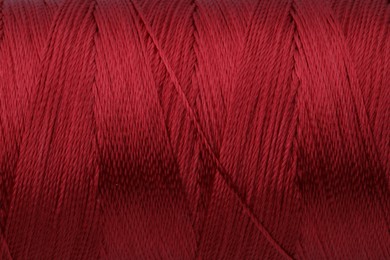 Photo of Beautiful red sewing thread as background, closeup