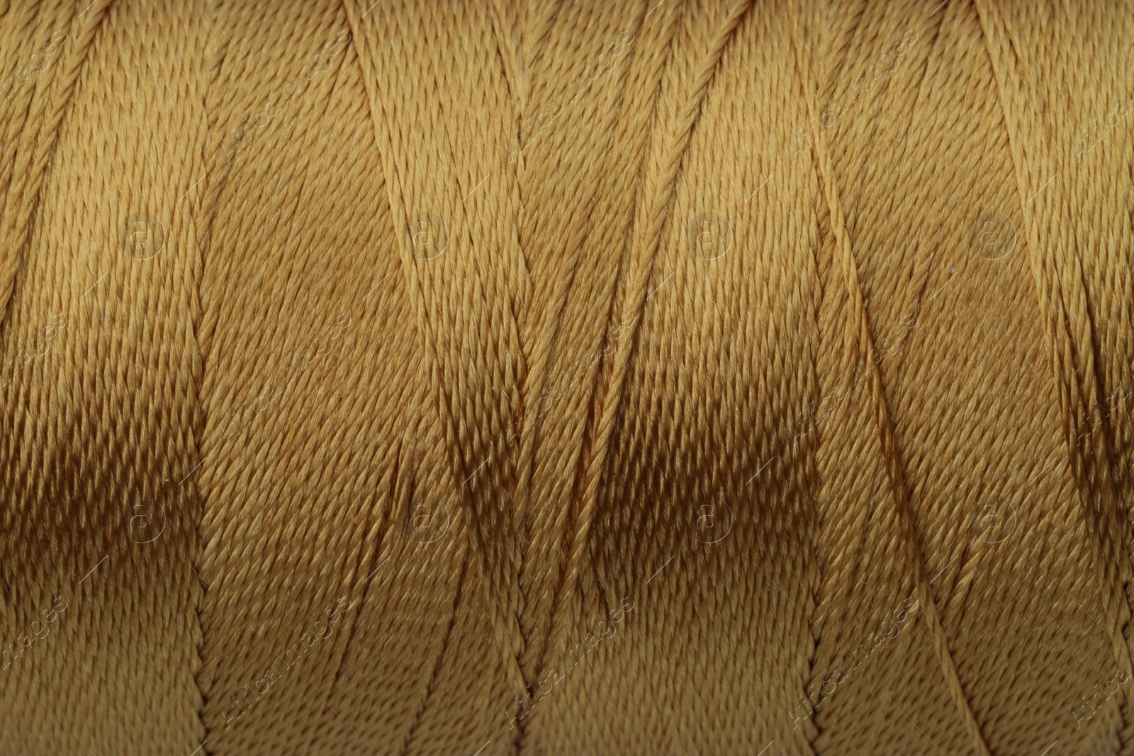 Photo of Light brown sewing thread as background, closeup