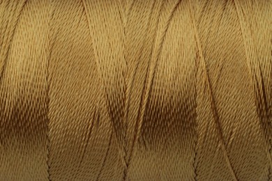 Photo of Light brown sewing thread as background, closeup