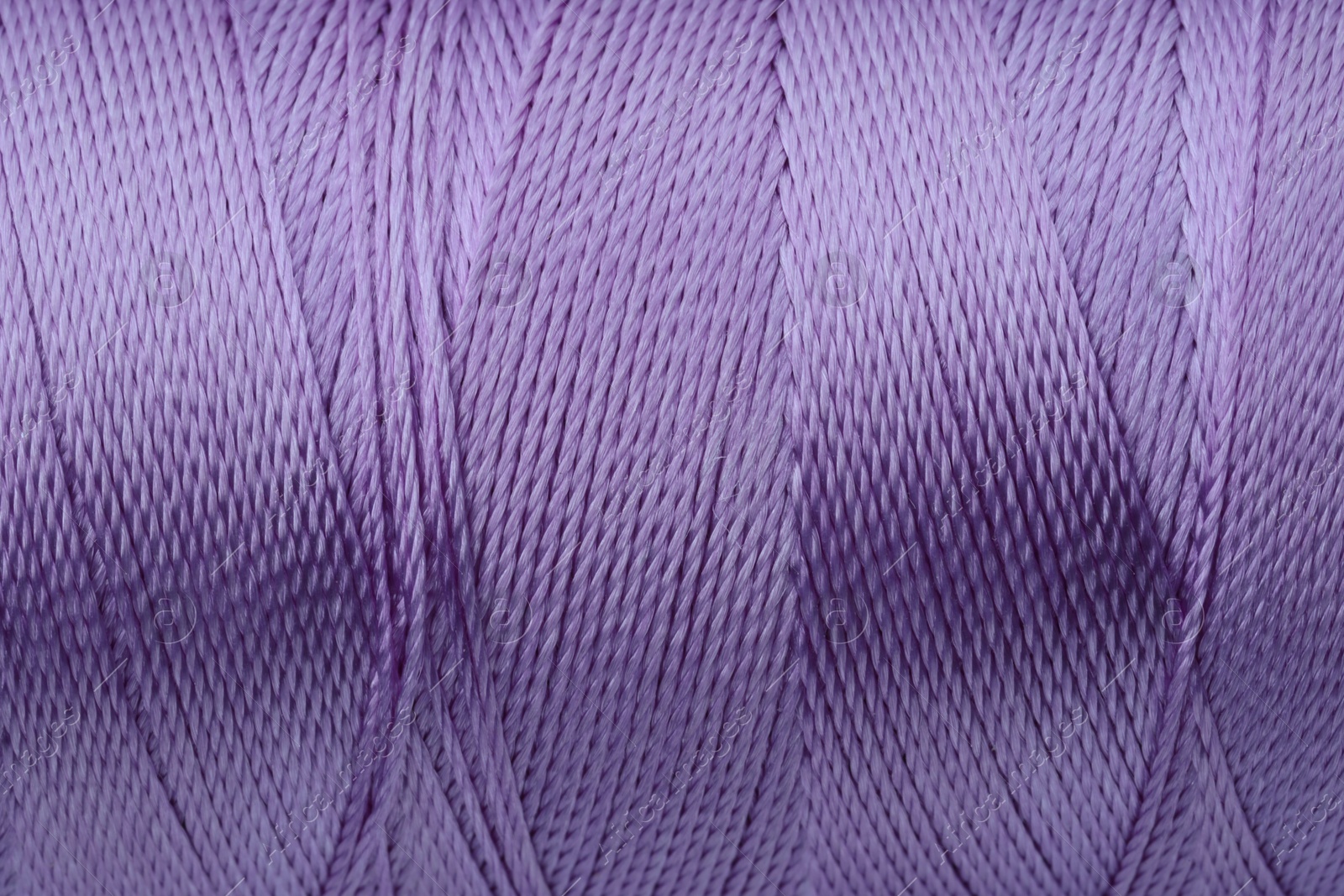 Photo of Beautiful violet sewing thread as background, closeup