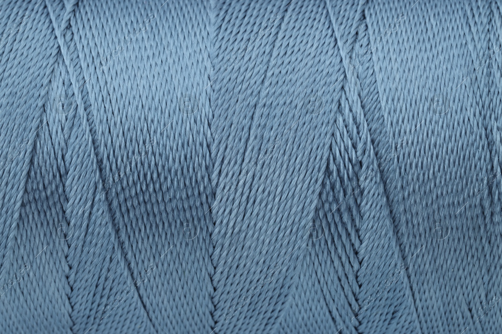 Photo of Beautiful blue sewing thread as background, closeup