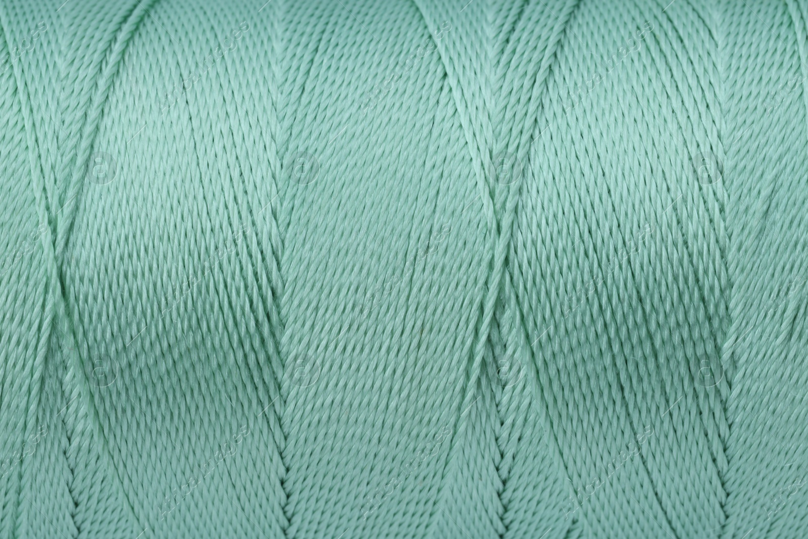 Photo of Beautiful turquoise sewing thread as background, closeup