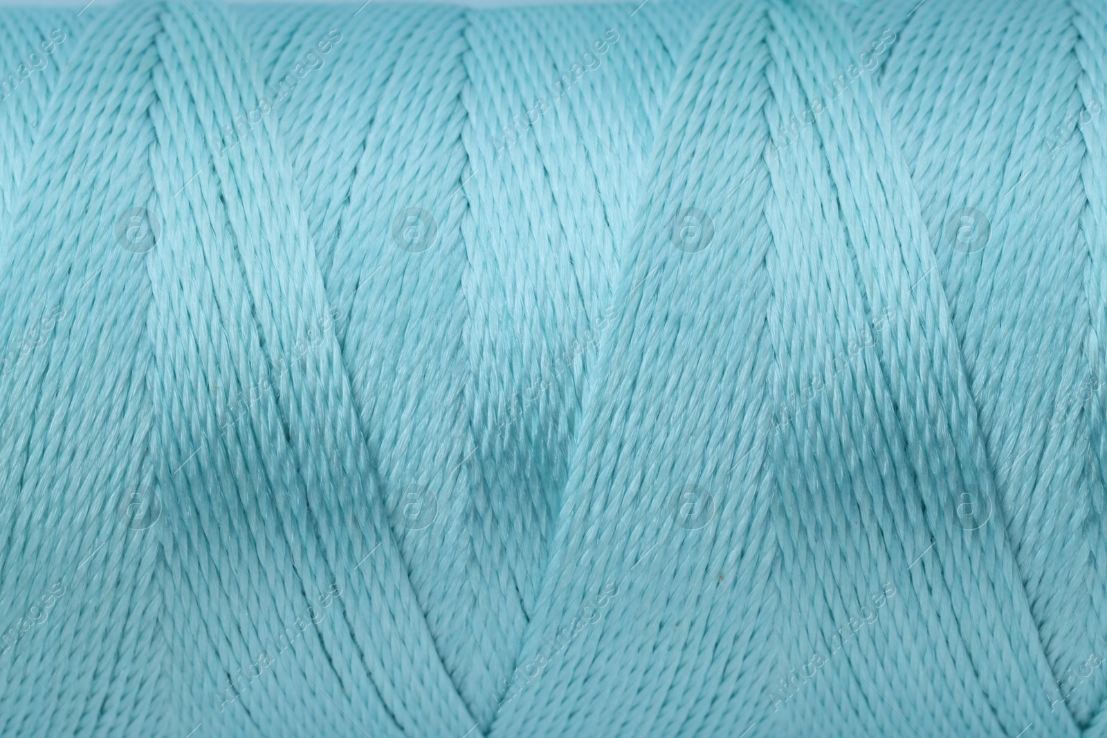 Photo of Light blue sewing thread as background, closeup