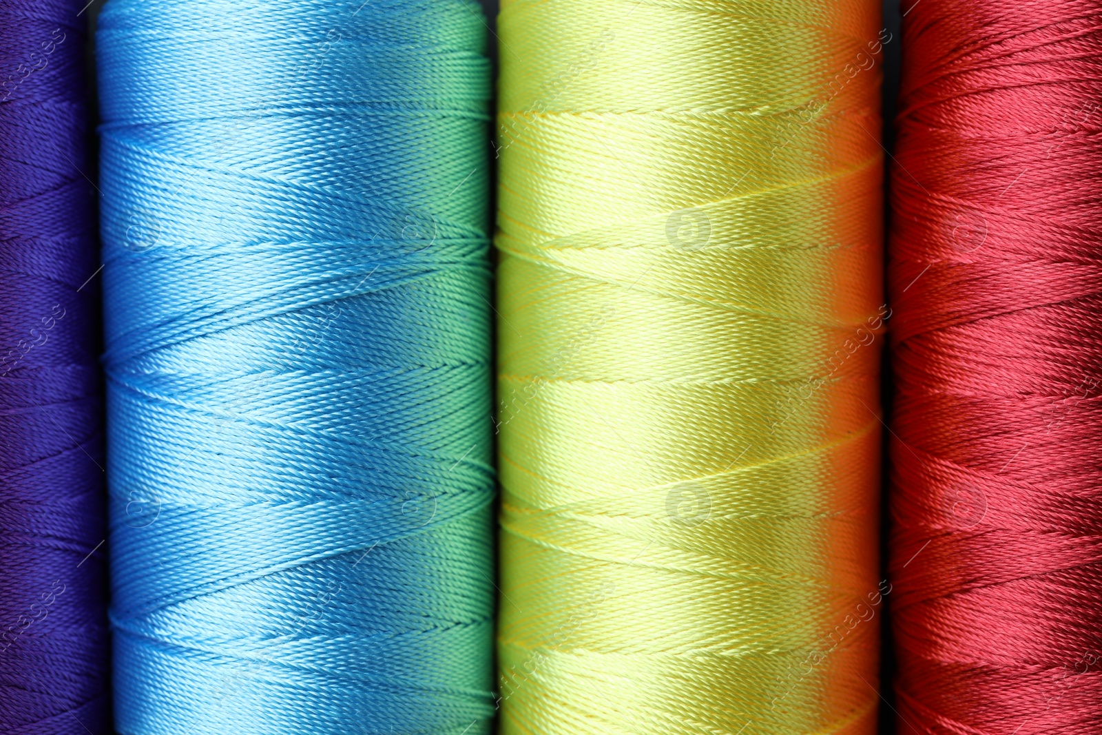 Photo of Spools of bright sewing threads as background, top view