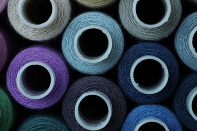 Photo of Spools of colorful sewing threads as background, top view