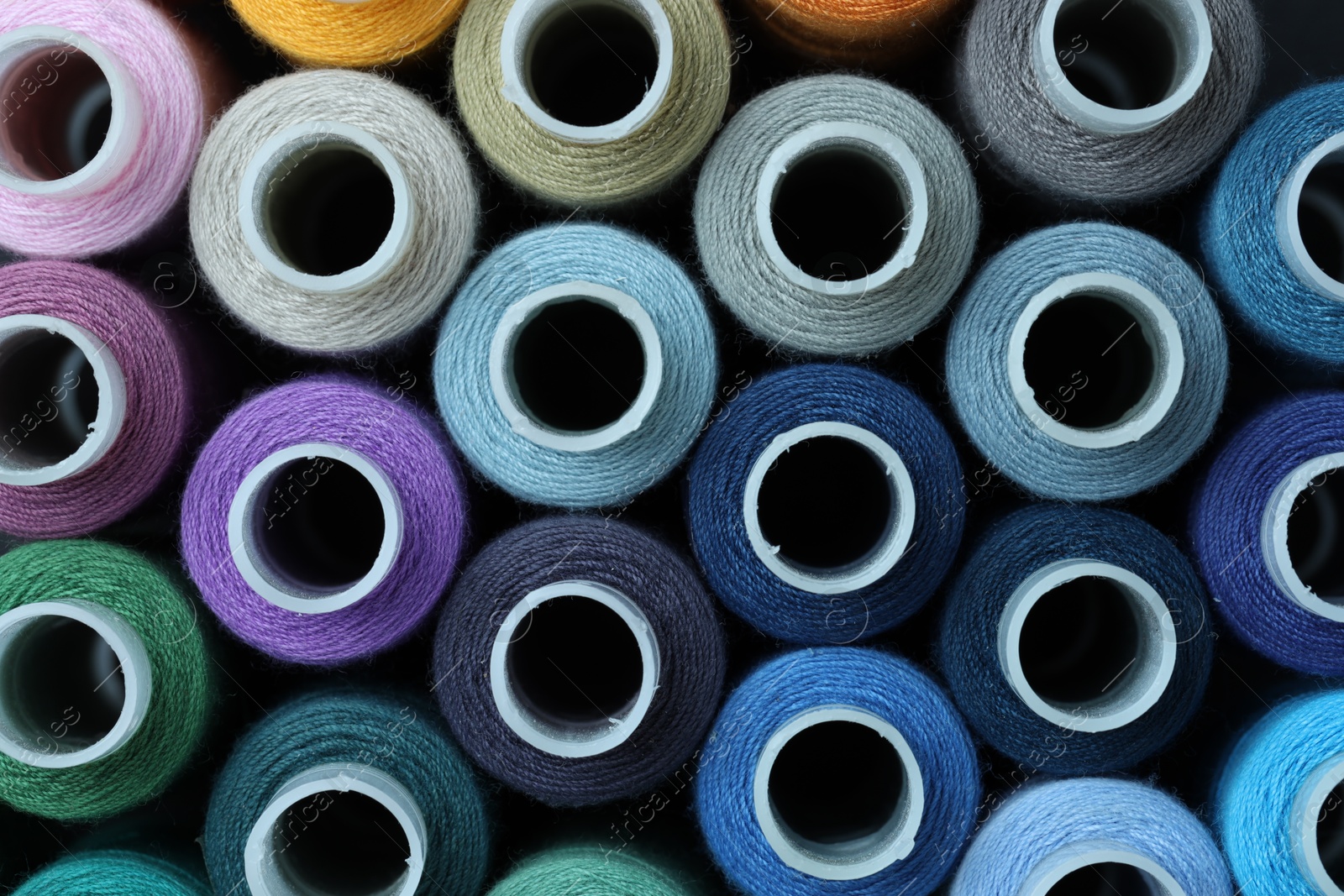 Photo of Spools of colorful sewing threads as background, top view