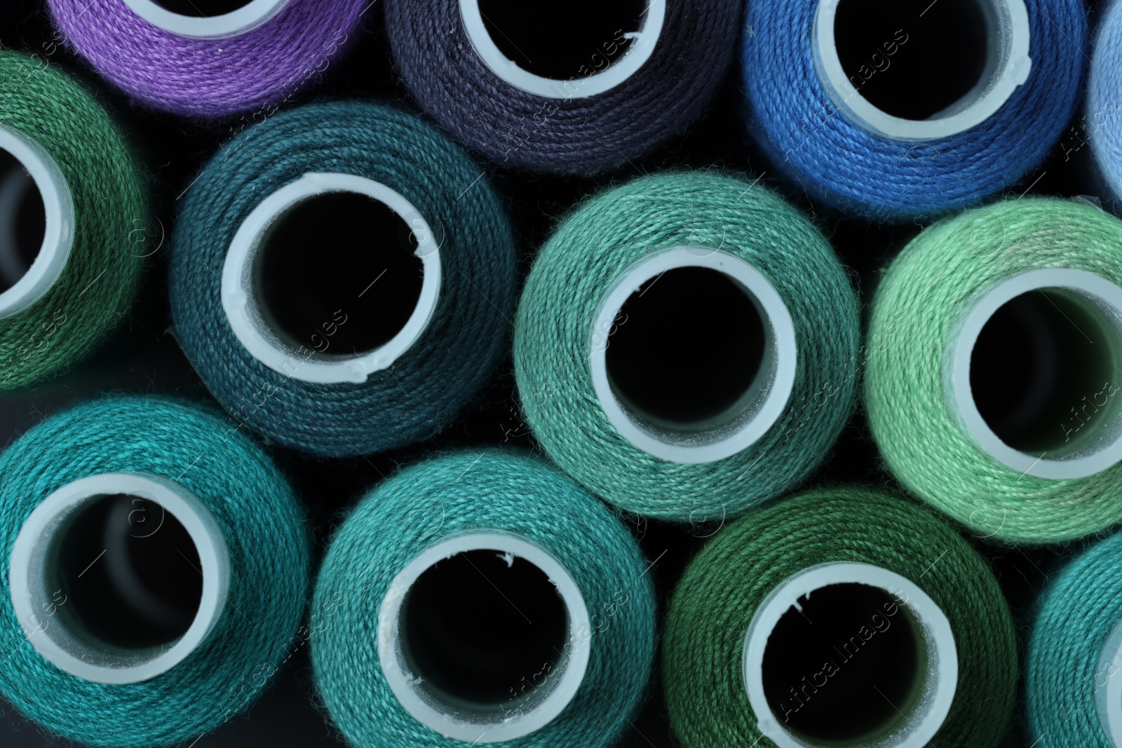 Photo of Spools of colorful sewing threads as background, top view