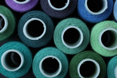 Photo of Spools of colorful sewing threads as background, top view