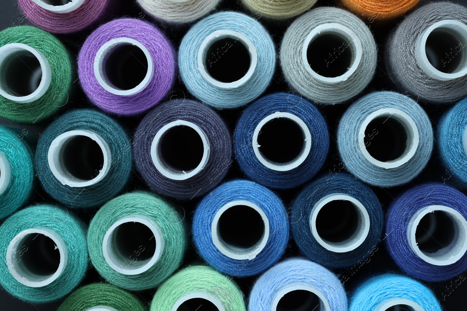 Photo of Spools of colorful sewing threads as background, top view