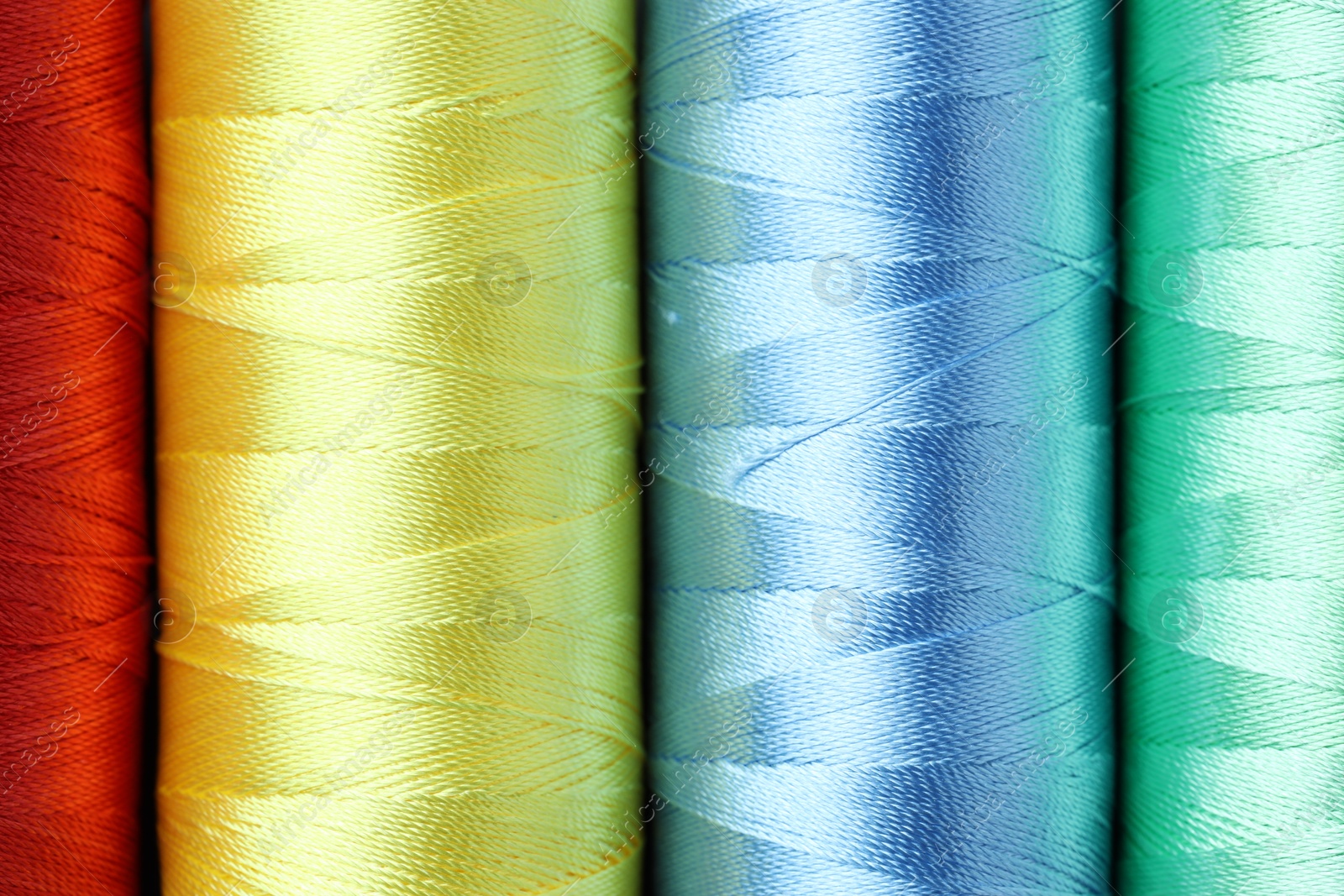 Photo of Spools of colorful sewing threads as background, top view