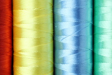 Photo of Spools of colorful sewing threads as background, top view