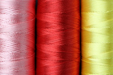 Photo of Spools of colorful sewing threads as background, top view