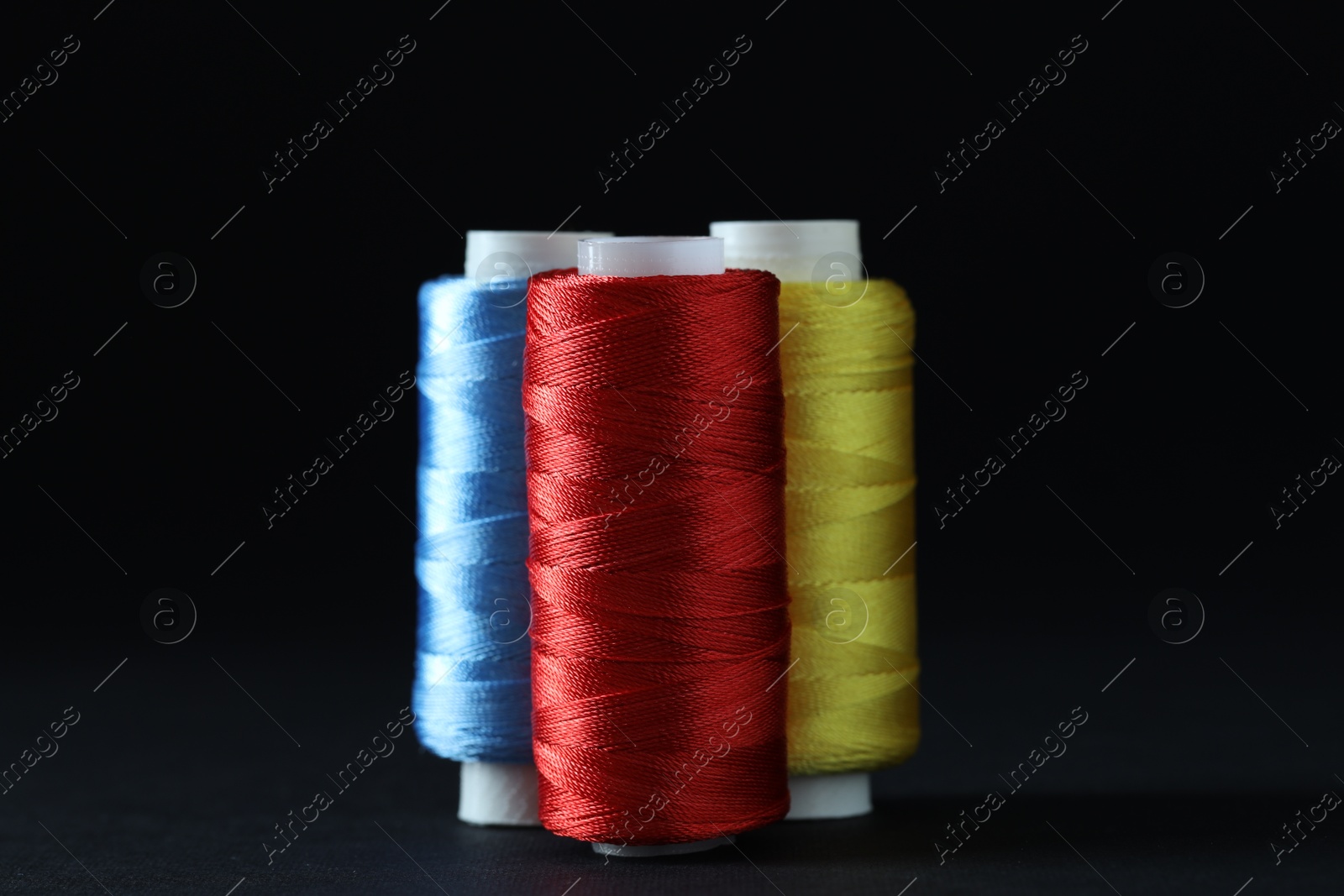 Photo of Spools of colorful sewing threads on black background