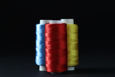 Photo of Spools of colorful sewing threads on black background