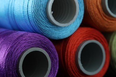 Photo of Spools of colorful sewing threads as background, closeup