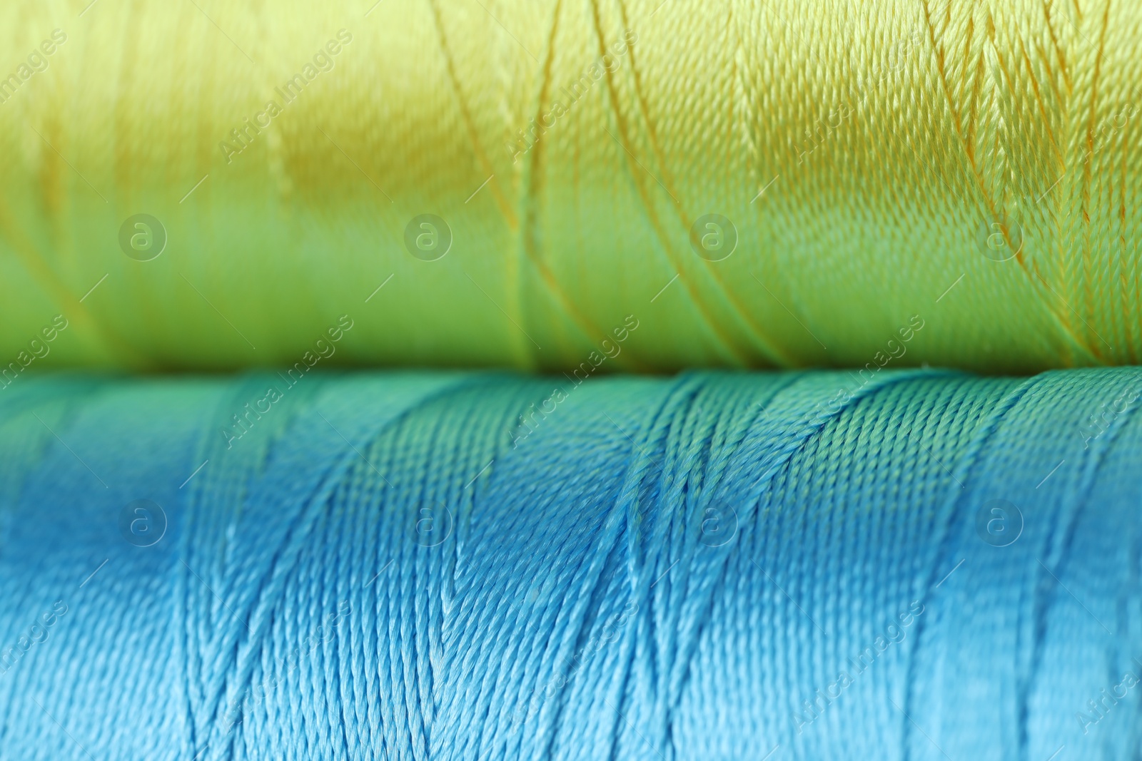 Photo of Spools of colorful sewing threads as background, closeup