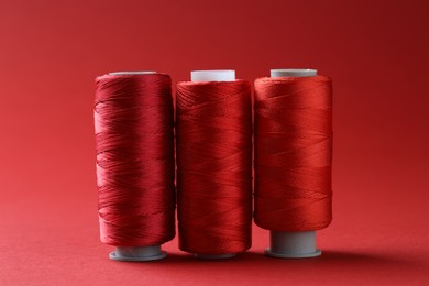 Photo of Spools of bright sewing threads on red background