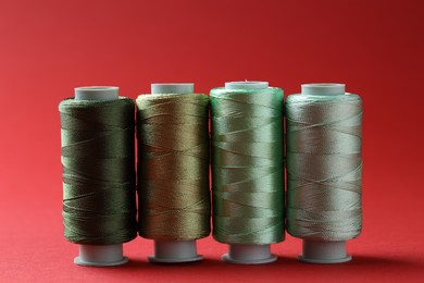 Photo of Spools of colorful sewing threads on red background