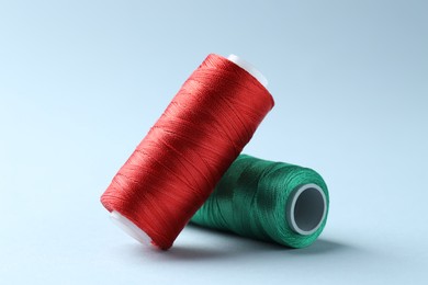 Photo of Spools of colorful sewing threads on light background