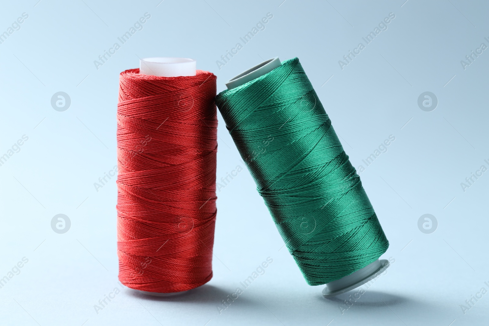 Photo of Spools of colorful sewing threads on light background