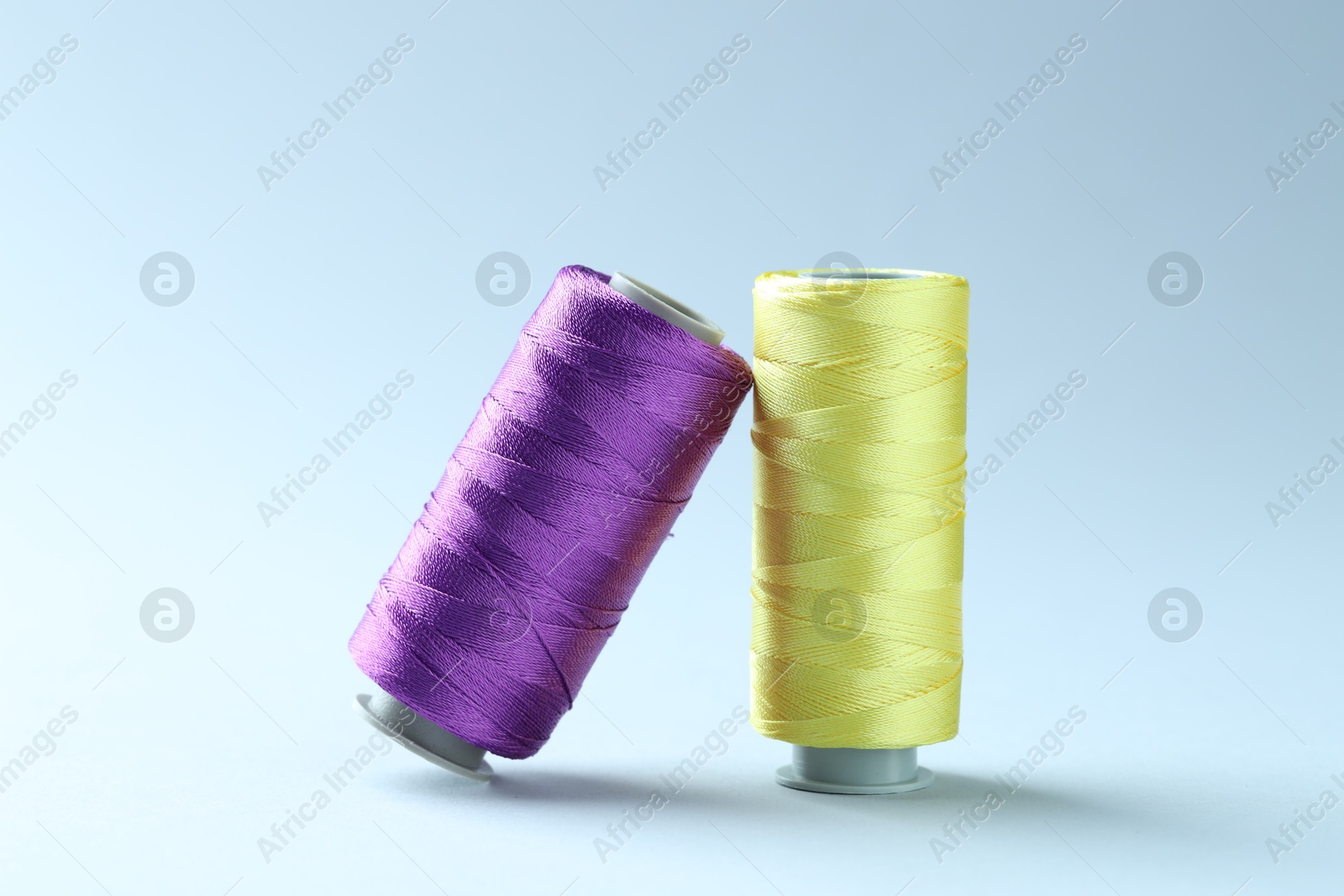 Photo of Spools of colorful sewing threads on light background