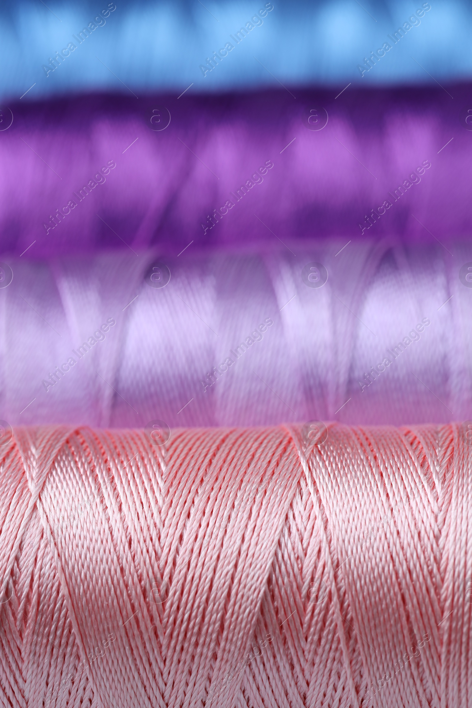 Photo of Spools of colorful sewing threads as background, closeup