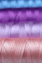 Photo of Spools of colorful sewing threads as background, closeup